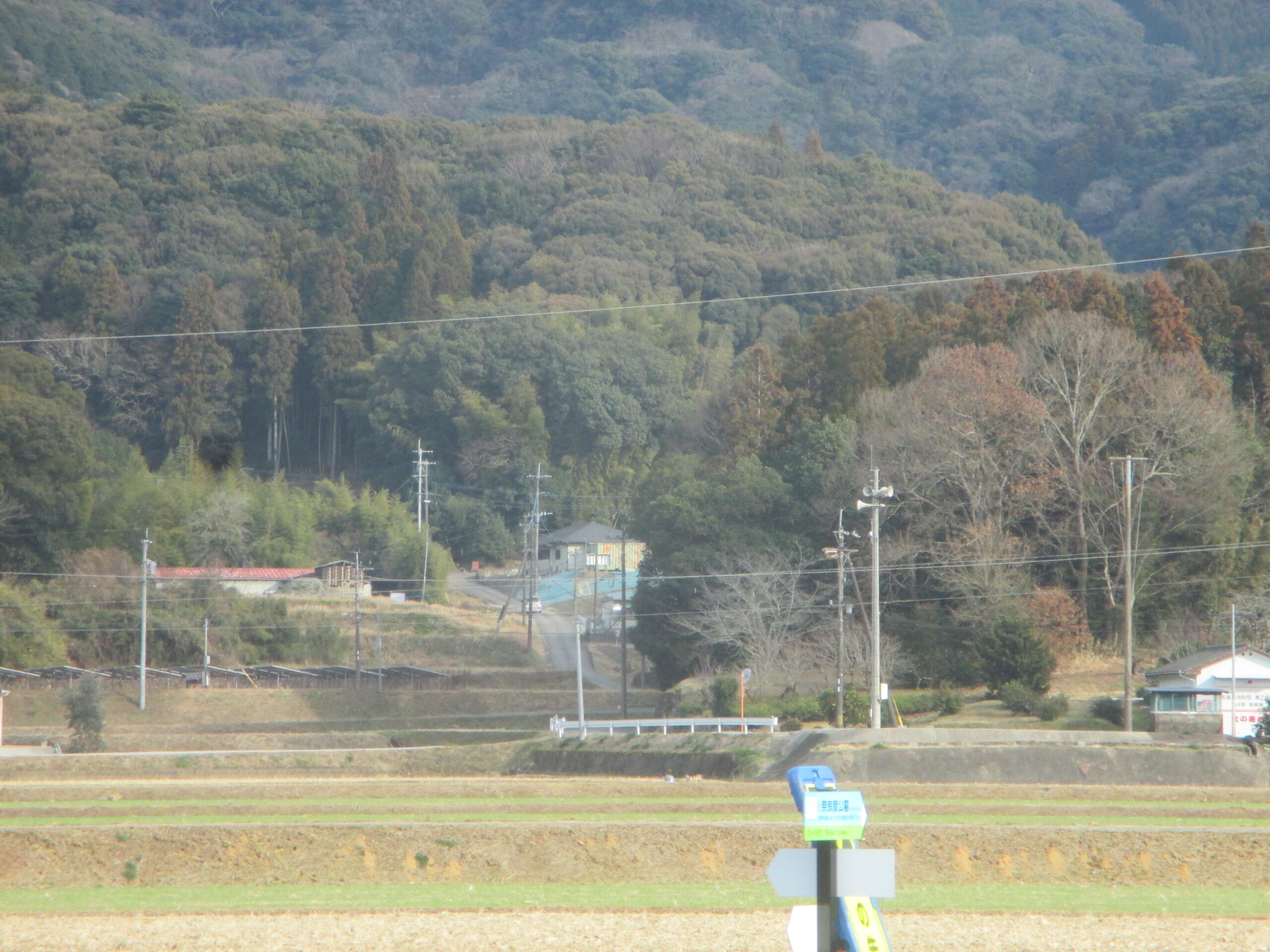 写真② 草場遺跡（左側代地）と北楢崎古墳群（右の尾根と背後の山）